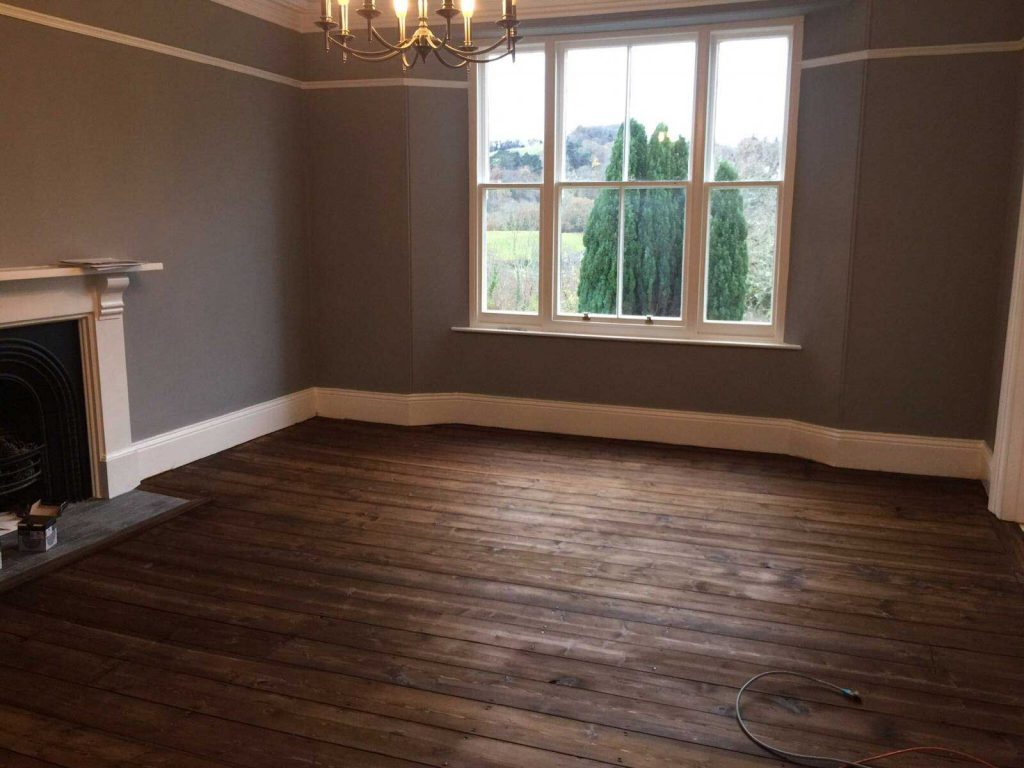 The wooden floor boards are sanded then stained with a Dark Oak Staining